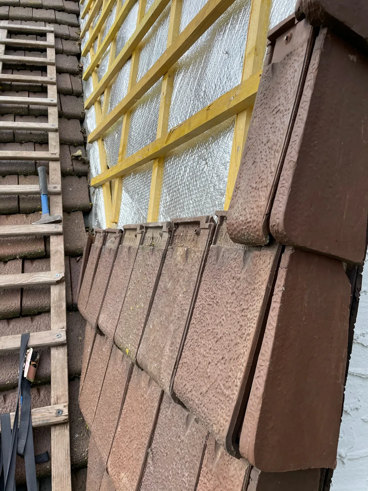 Détail de l'isolant mince réflecteur derrière les tuiles reposées avec lame d'air, couvreur à Saint-Arnoult-en-Yvelines