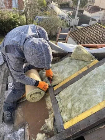 Artisan posant de la laine de verre entre les chevrons d'une toiture